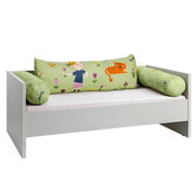 Kinderbed met een groene kussensloop, voorzien van een afbeelding van een kind, een kat en bloemen, gezien vanuit een zijaanzicht
