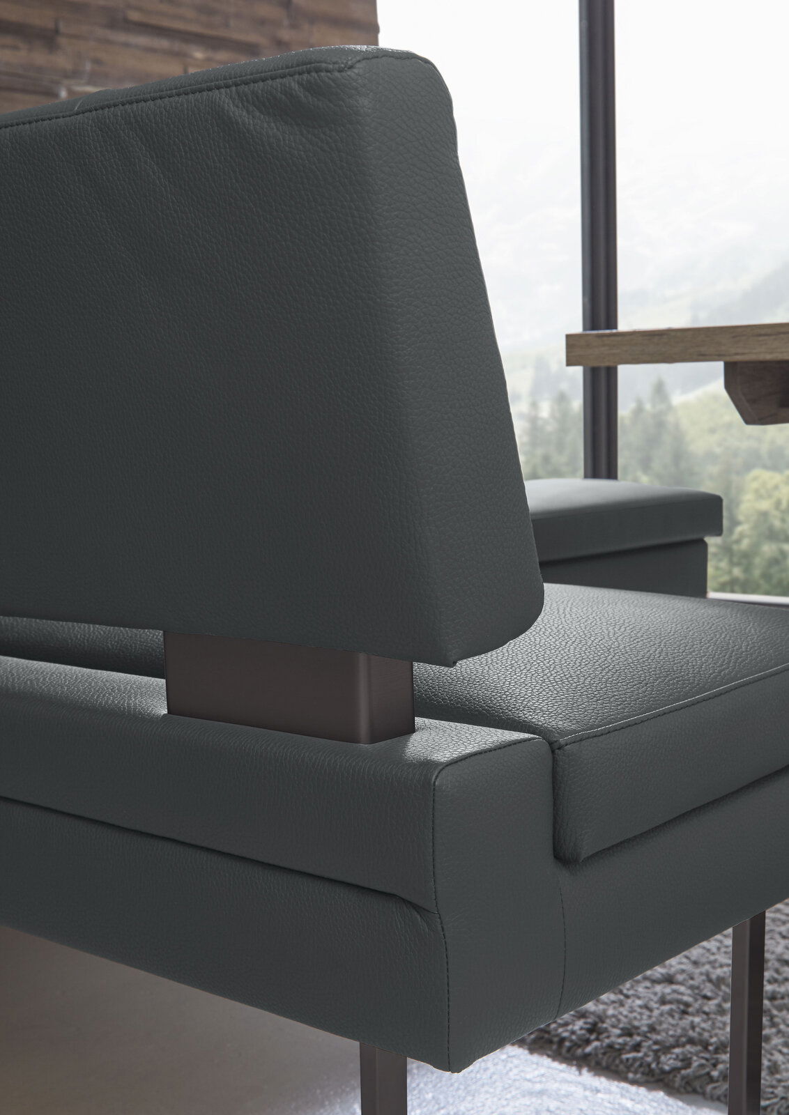 Nahaufnahme einer modernen Eckbank mit dunkelgrauem Lederbezug und Metallgestell, seitliche Perspektive.