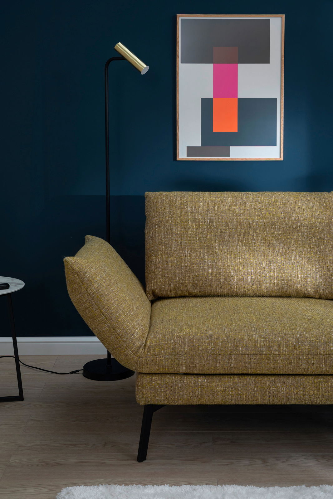 Gelbes Longchair-Sofa in modernem Wohnzimmer, seitliche Perspektive mit Stehlampe und abstraktem Kunstwerk an der Wand.