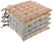 Stapel von vier Sitzkissen in verschiedenen Farben, von oben nach unten: rosa, grün, blau und beige, aus seitlicher Perspektive fotografiert.