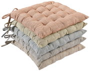 Stapel von vier Sitzkissen in verschiedenen Farben, von oben nach unten: rosa, grün, blau und beige, aus seitlicher Perspektive fotografiert.