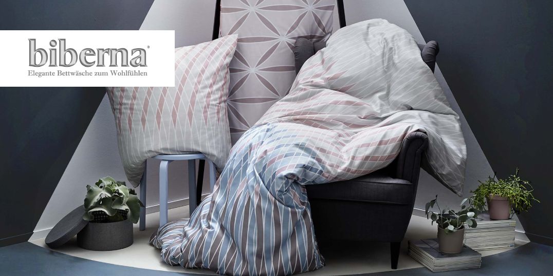 Auf einem Sessel drapierte Biberna-Bettwäsche und Kissen.