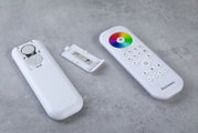 Fernbedienung mit abgenommenem Batteriefachdeckel, zeigt Batterien und bunte Steuerungstasten, von oben betrachtet.