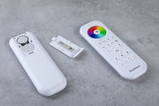 Fernbedienung mit abgenommenem Batteriefachdeckel, zeigt Batterien und bunte Steuerungstasten, von oben betrachtet.