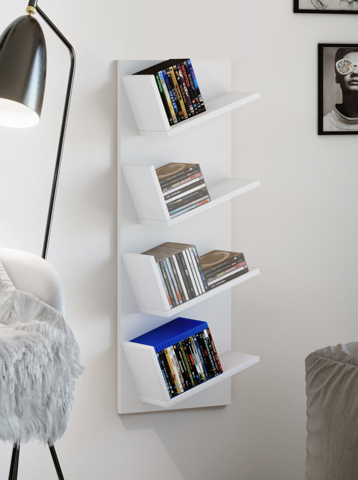 Weißes, wandmontiertes Regal mit vier schrägen Ablagen für DVDs und CDs, befüllt, in moderner Wohnraum-Szene; Ansicht leicht schräg von vorne.
