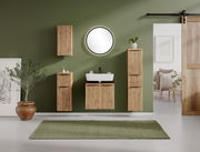 Runder Spiegel an einer grünen Wand in einem stilvoll eingerichteten Badezimmer mit Holzschränken und Pflanzen, Frontalansicht.