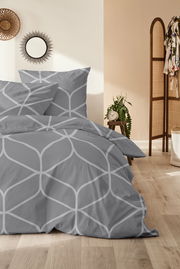 Graue Bettwäsche mit geometrischem Muster in einem stilvoll eingerichteten Schlafzimmer, seitliche Perspektive