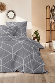 Graue Bettwäsche mit geometrischem Muster in einem stilvoll eingerichteten Schlafzimmer, seitliche Perspektive