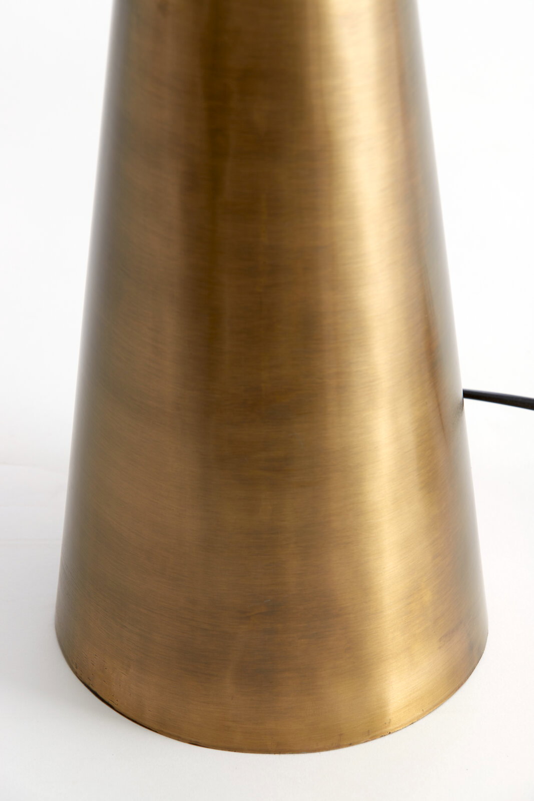 Nahaufnahme eines konischen Lampenfußes aus gebürstetem Metall in goldener Farbe, seitliche Perspektive.