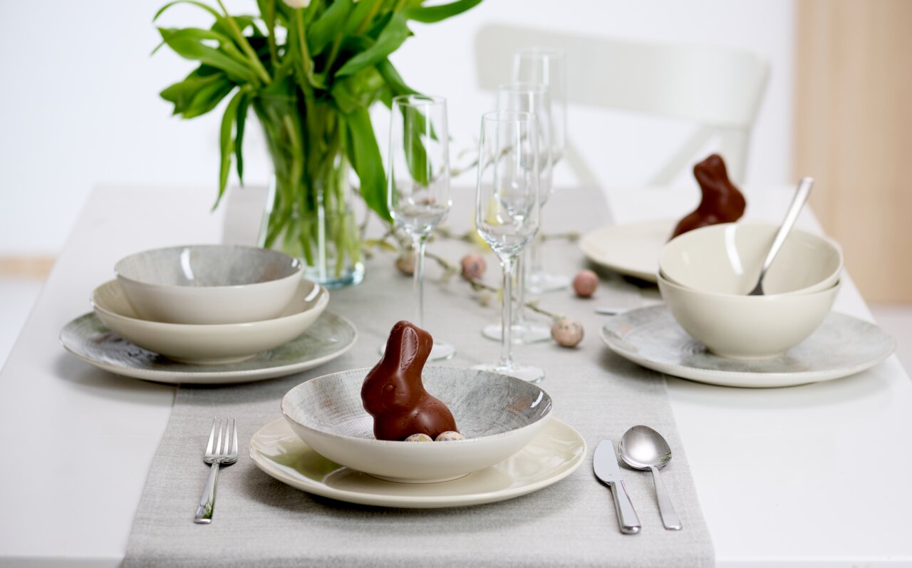 Ritzenhoff & Breker Tafelservice 18-tlg. CECINA Elegantes 18-teiliges Geschirrset auf einem gedeckten Tisch mit Frühlingsdekoration, aus der Perspektive von vorne betrachtet.