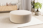 Runder, cremefarbener Pouf/Polsterhocker mit weichem Bouclé-Bezug im modernen Wohnzimmer auf hellem Teppich, Perspektive: leicht erhöhte Frontansicht.