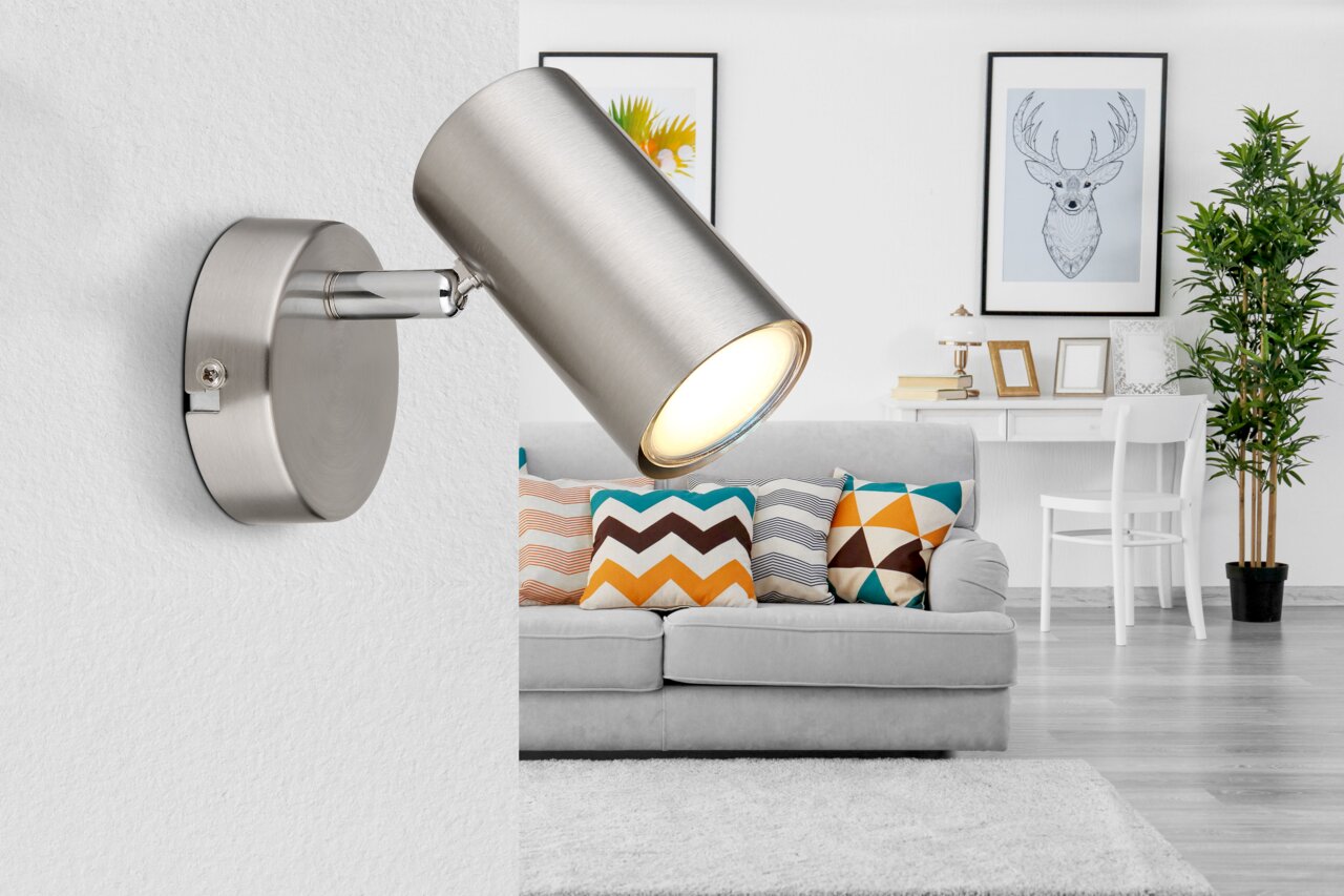 Moderne wandspot van geborsteld metaal in een stijlvolle woonkamer, gezien vanaf de zijkant.