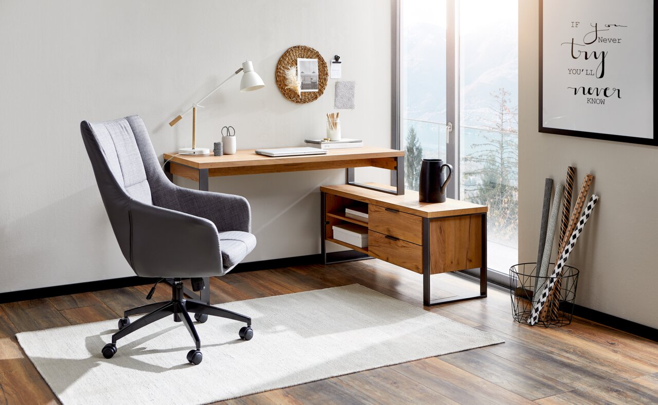 Moderner Eck-Schreibtisch aus Holz mit Metallrahmen, abgebildet in einem hellen Raum mit großem Fenster und stilvollem Bürostuhl, aus der Perspektive von vorne links.