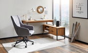 Moderner Eck-Schreibtisch aus Holz mit Metallrahmen, abgebildet in einem hellen Raum mit großem Fenster und stilvollem Bürostuhl, aus der Perspektive von vorne links.