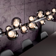 Moderne LED-Pendelleuchte mit mehreren kugelförmigen Glaskörpern, von oben fotografiert, über einem Esstisch hängend.