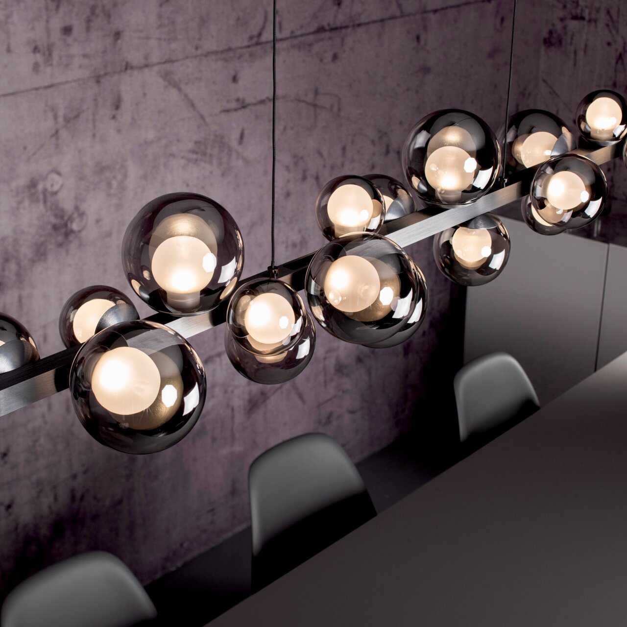 Moderne LED-Pendelleuchte mit mehreren kugelförmigen Glaskörpern, von oben fotografiert, über einem Esstisch hängend.
