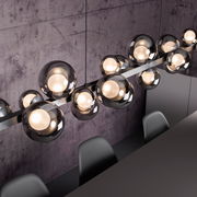 Moderne LED-Pendelleuchte mit mehreren kugelförmigen Glaskörpern, von oben fotografiert, über einem Esstisch hängend.