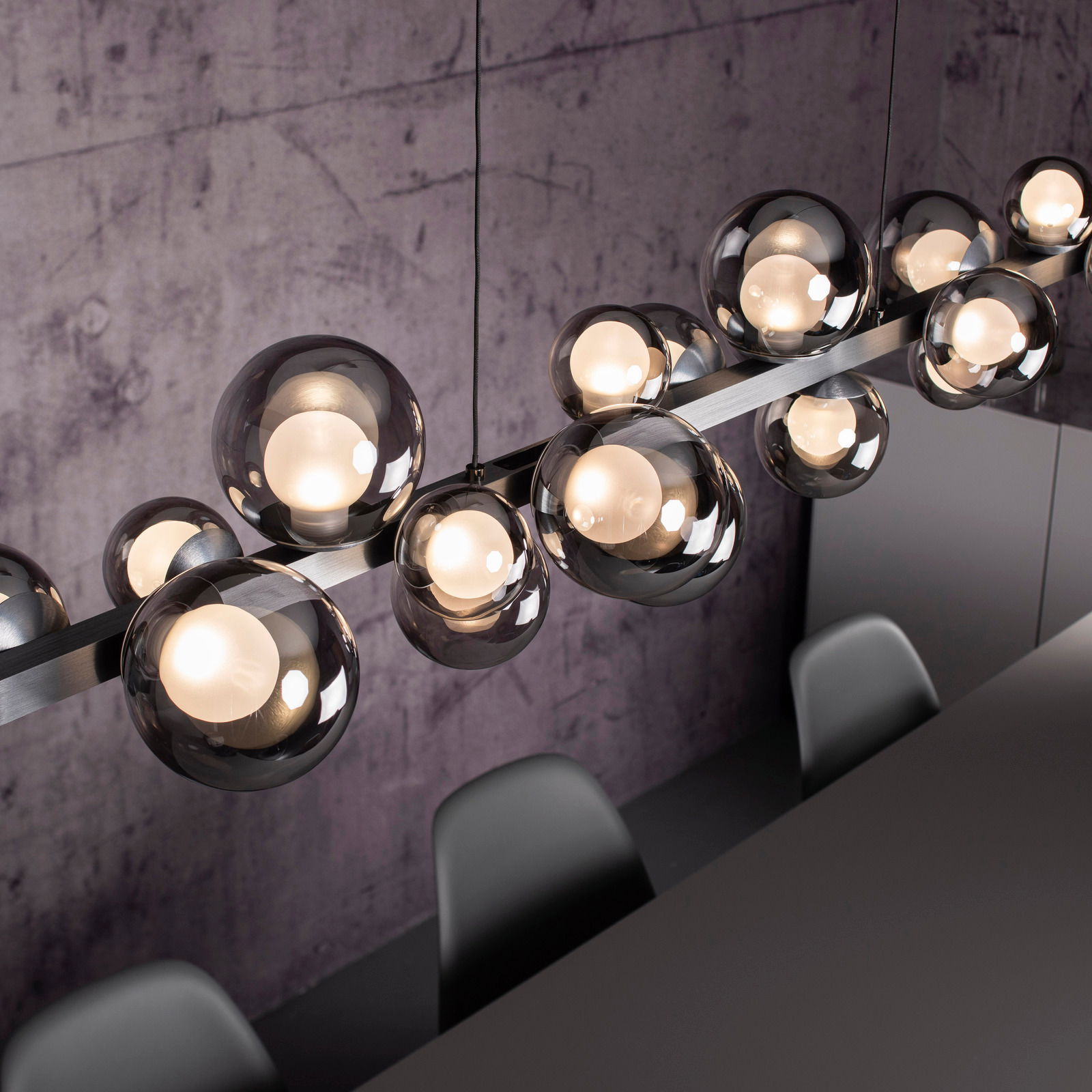 Moderne LED-Pendelleuchte mit mehreren kugelförmigen Glaskörpern, von oben fotografiert, über einem Esstisch hängend.