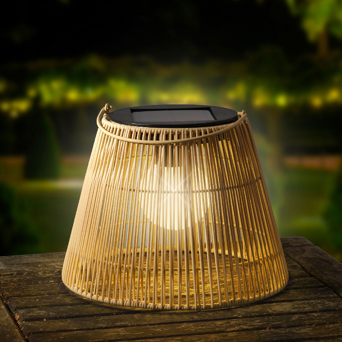 Solarbetriebene Laterne aus geflochtenem Material auf einem Holztisch, leuchtend in der Abenddämmerung, seitliche Perspektive