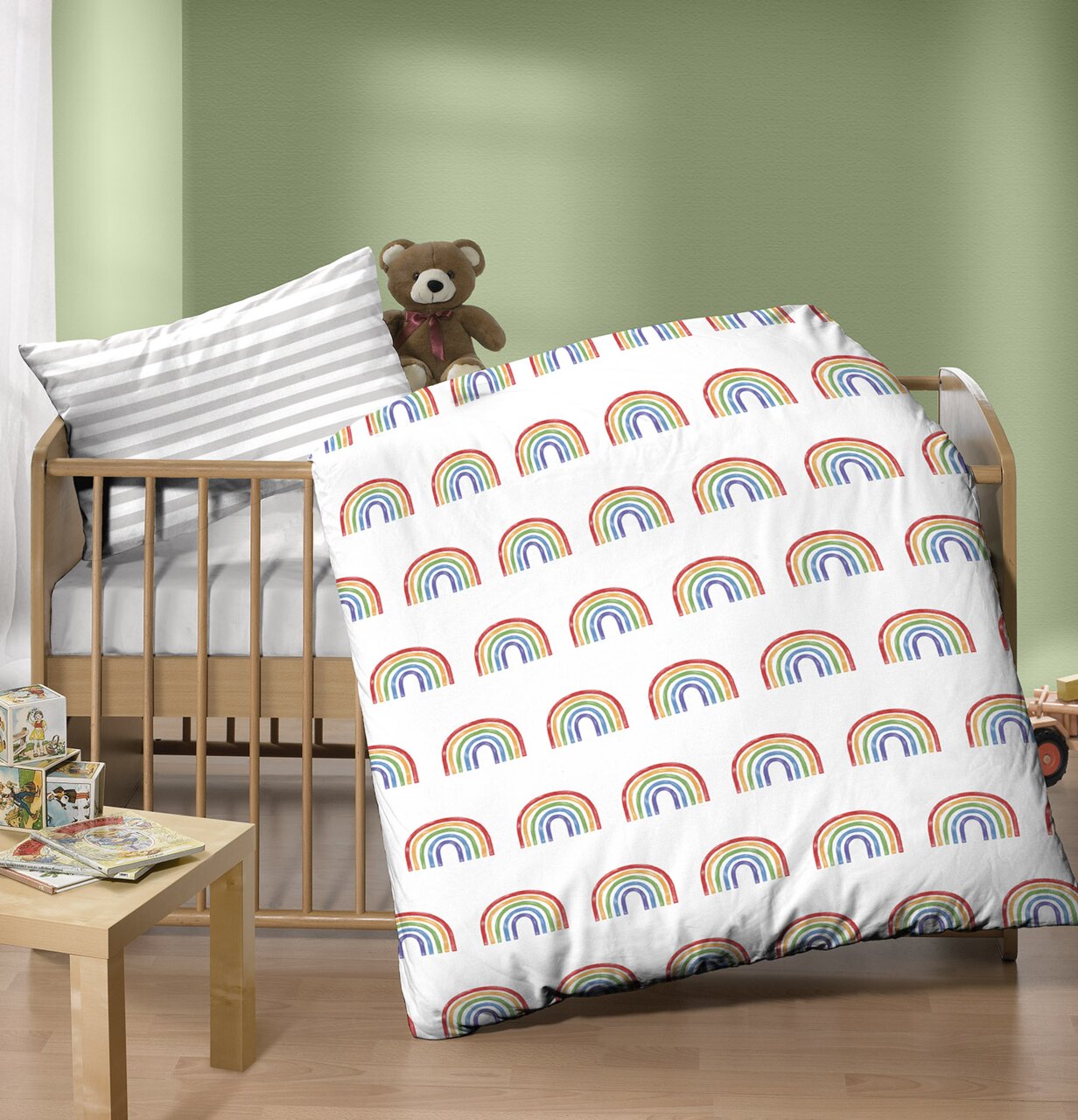 Kinderbett mit bunter Regenbogen-Bettwäsche und einem Teddybär, seitliche Perspektive