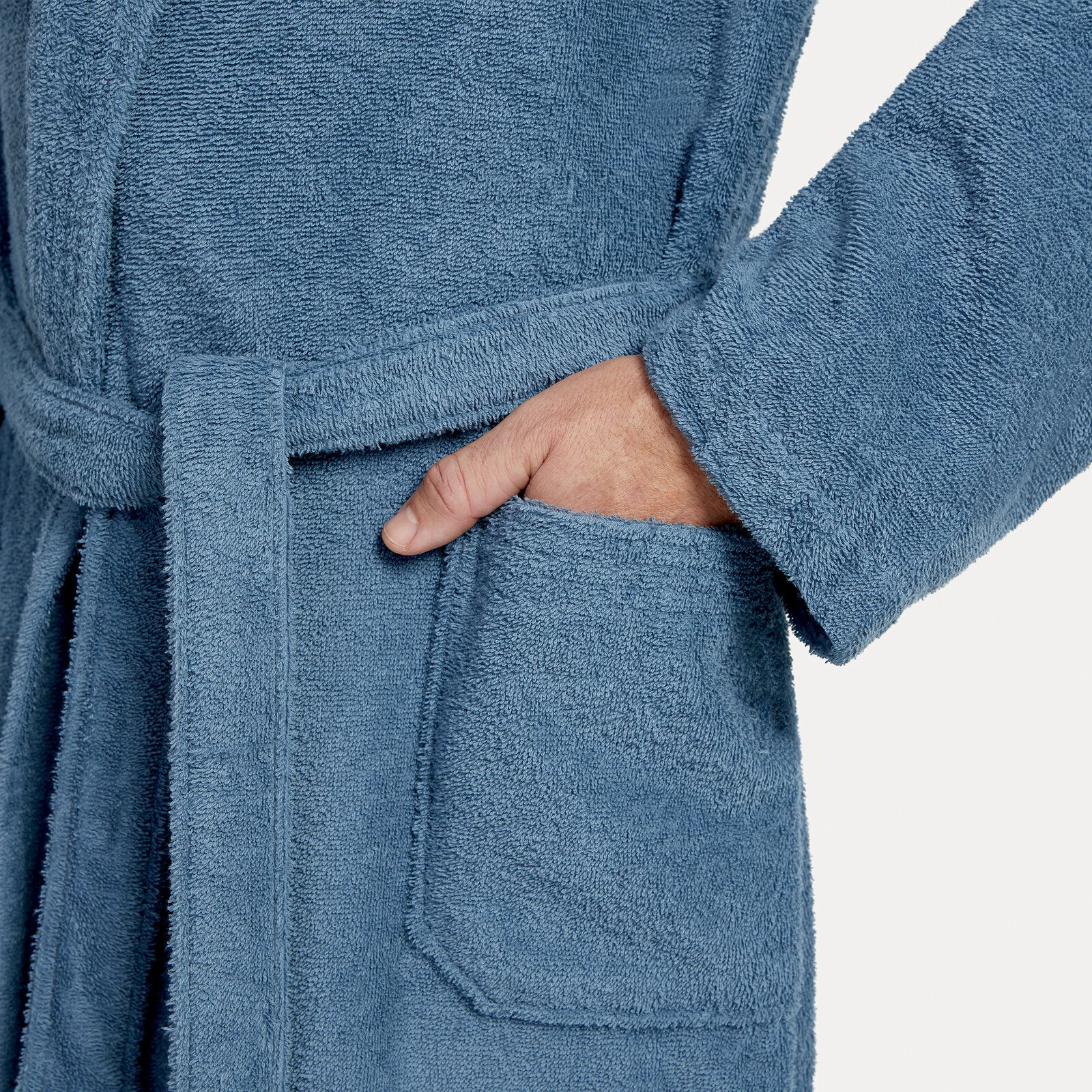 MÖVE Bademantel Schalkragen XS HOMEWEAR BASIC Nahaufnahme eines blauen Bademantels mit Schalkragen, einer Hand in der Tasche und einem Gürtel um die Taille.