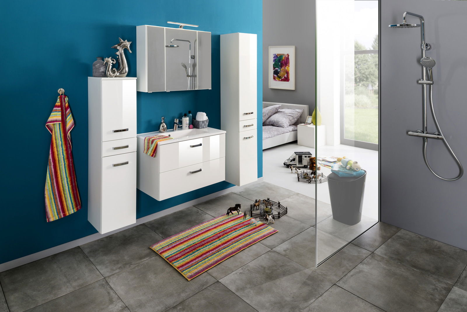 Moderner Waschplatz mit weißen Schränken und Spiegel, bunte Akzente durch Handtuch und Teppich, seitliche Perspektive