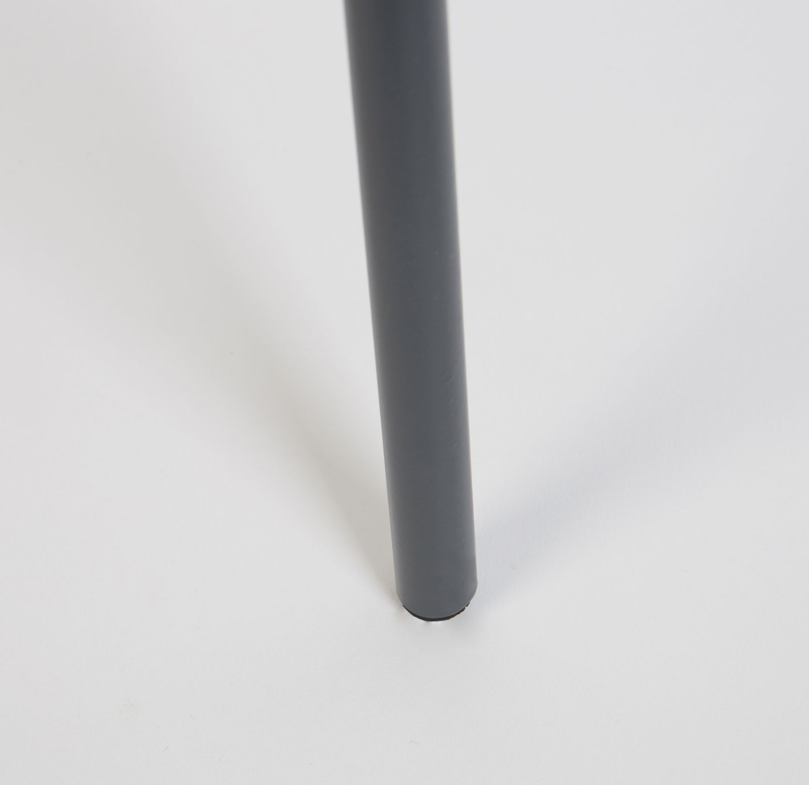 Nahaufnahme eines Tischbeins eines Beistelltisches in dunkler Farbe, von der Seite betrachtet.