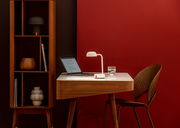 Moderner Schreibtisch mit weißer Tischlampe und Laptop, seitliche Perspektive