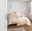 Elegante Bettwäsche in Cremefarben mit floralem Muster, auf einem Bett in einem hellen, modernen Schlafzimmer, seitliche Perspektive.