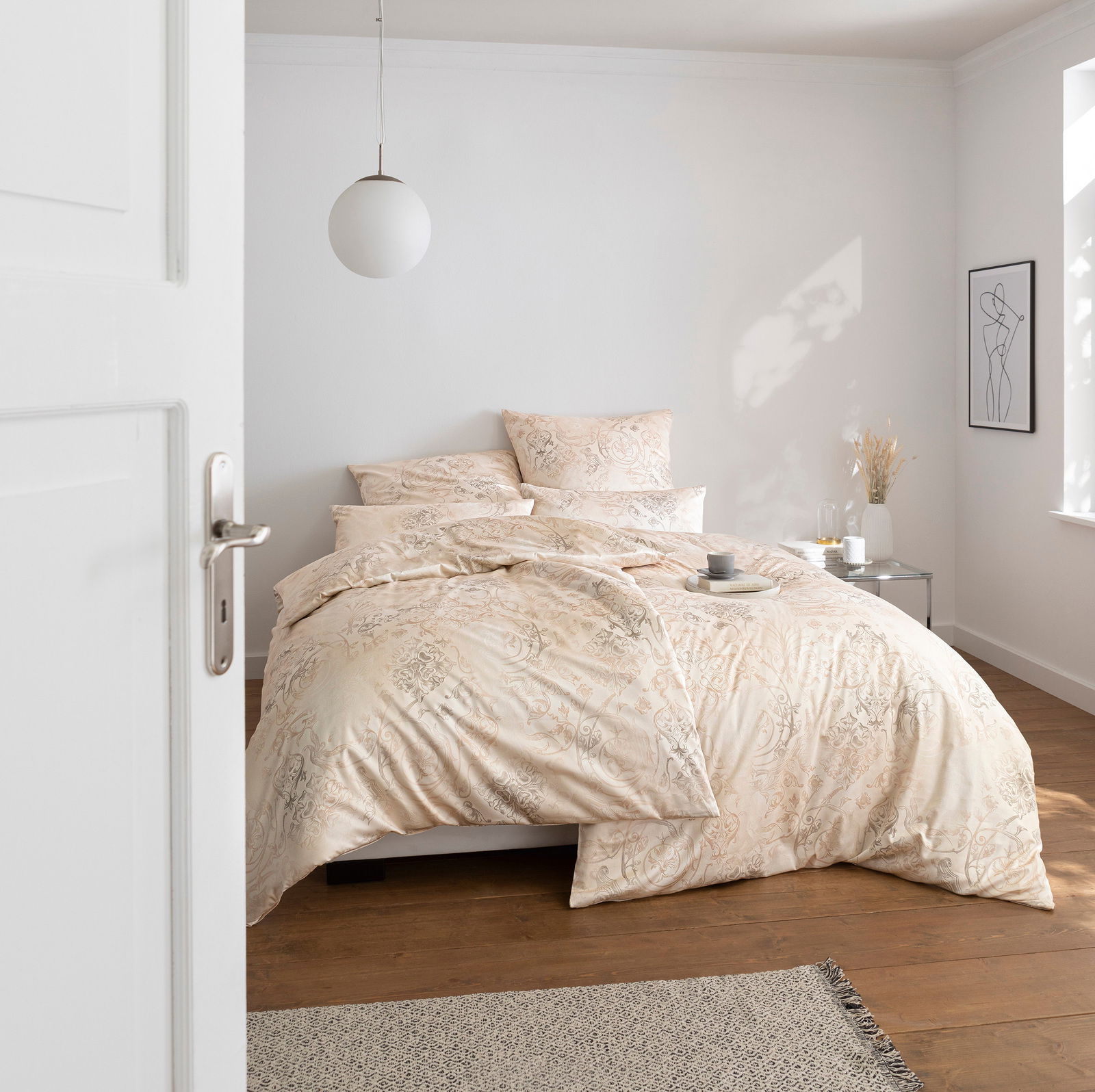 Elegante Bettwäsche in Cremefarben mit floralem Muster, auf einem Bett in einem hellen, modernen Schlafzimmer, seitliche Perspektive.