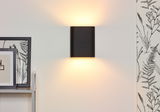 Schwarze Wandleuchte OVALIS von Lucide, die warmes Licht nach oben und unten abstrahlt, seitliche Perspektive.