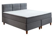 Graues Boxspringbett mit gepolstertem Kopfteil, seitliche Perspektive