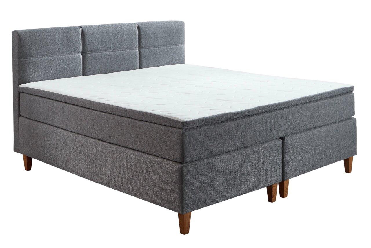 Graues Boxspringbett mit gepolstertem Kopfteil, seitliche Perspektive