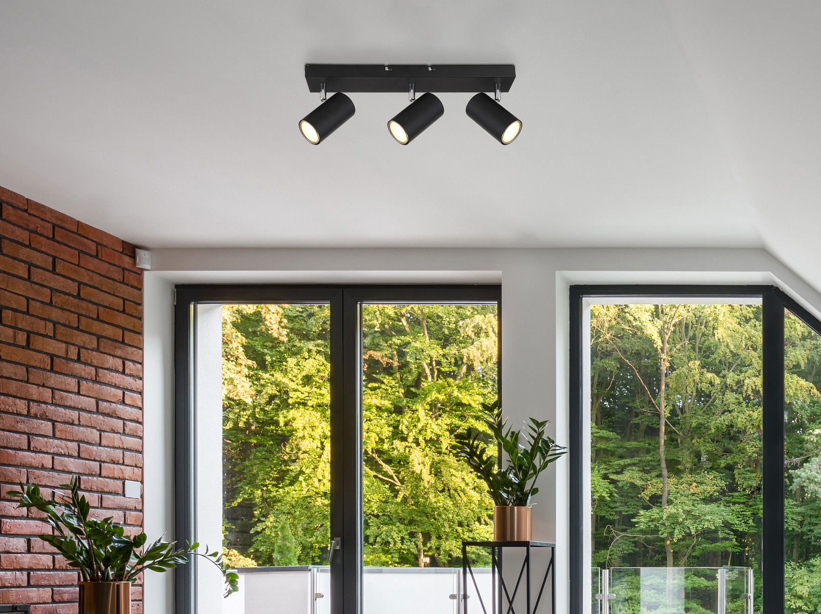 Moderner Deckenstrahler mit drei verstellbaren Leuchten in einem stilvollen Wohnzimmer, Perspektive von unten.