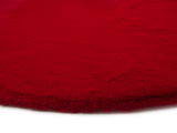 Roter Fellteppich aus der Nähe fotografiert, zeigt die flauschige Textur und die Kante des Teppichs.