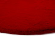 Roter Fellteppich aus der Nähe fotografiert, zeigt die flauschige Textur und die Kante des Teppichs.