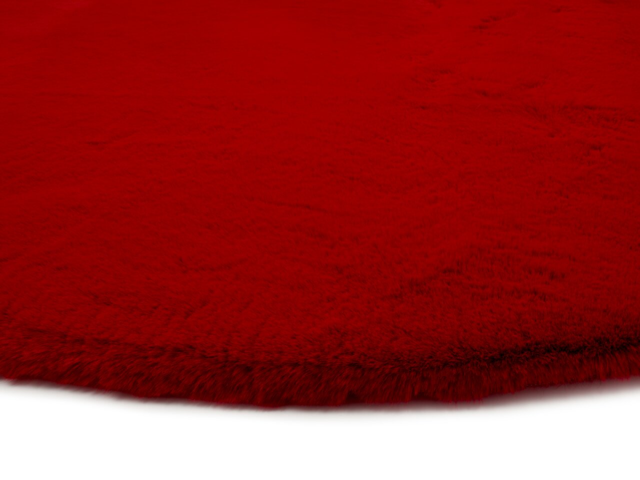 Roter Fellteppich aus der Nähe fotografiert, zeigt die flauschige Textur und die Kante des Teppichs.