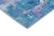 Nahaufnahme einer Ecke eines blauen Teppichs mit rosa und grauen Akzenten, perspektivisch von der Seite aufgenommen.