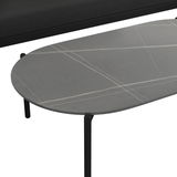 Nahaufnahme eines modernen, ovalen Couchtisches mit grauer Tischplatte und feinen weißen Linien, Teil einer Loungegarnitur. Perspektive von oben.