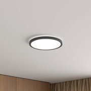 Runde, flache LED-Deckenleuchte mit dunklem Rahmen und diffuser Lichtfläche, an weißer Decke montiert, in leichter Untersicht von unten fotografiert