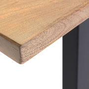 Nahaufnahme einer Tischkante aus Holz mit schwarzem Metallbein, Perspektive von oben.