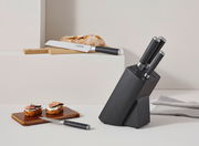 Moderner Messerblock mit sechs Teilen, darunter ein Brotmesser und ein kleines Messer, in einer stilvollen, schwarzen Halterung. Perspektive von vorne rechts.