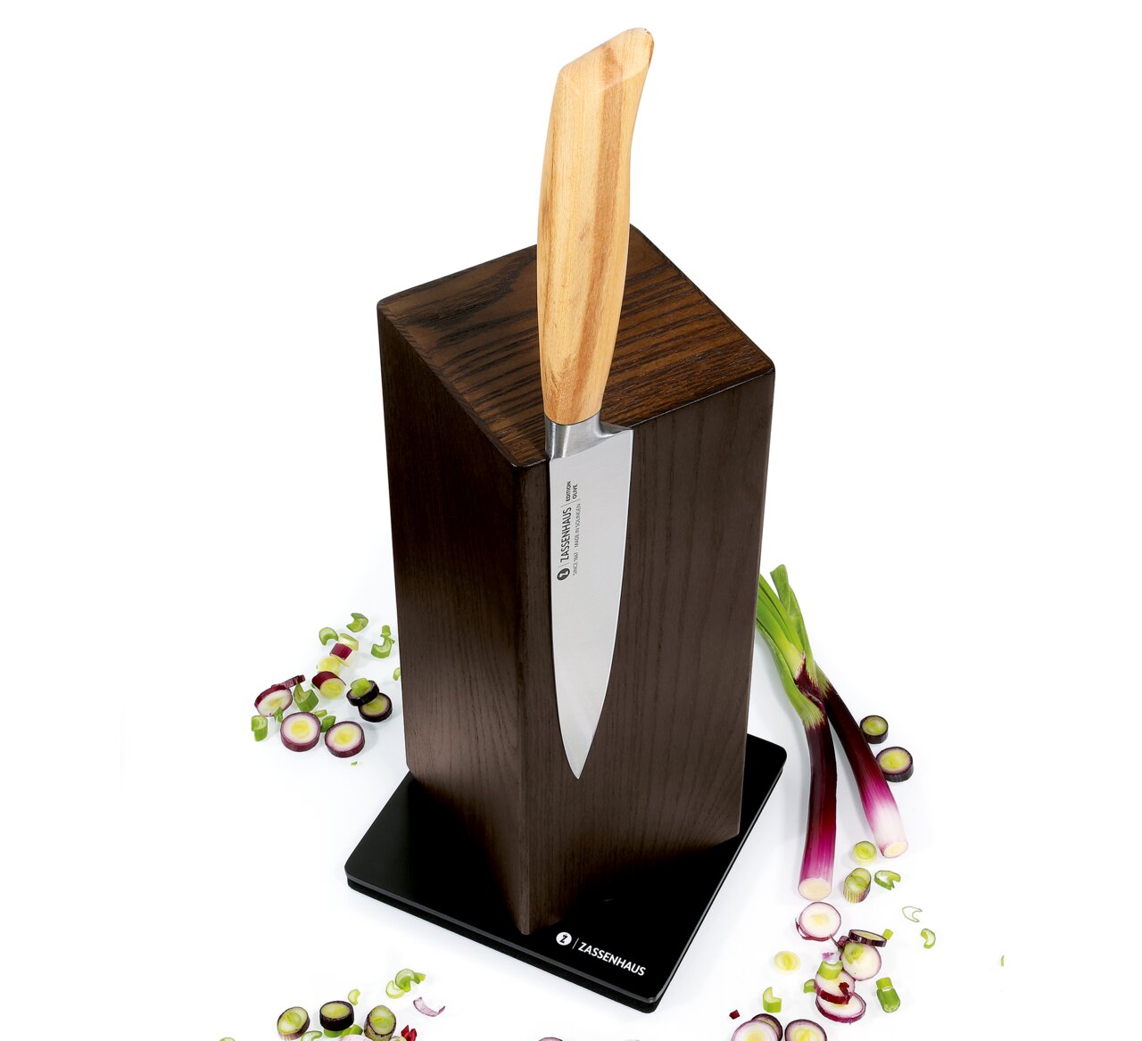 Magnet-Messerblock aus Esche mit einem Messer, umgeben von geschnittenen Frühlingszwiebeln, aus der Vogelperspektive.