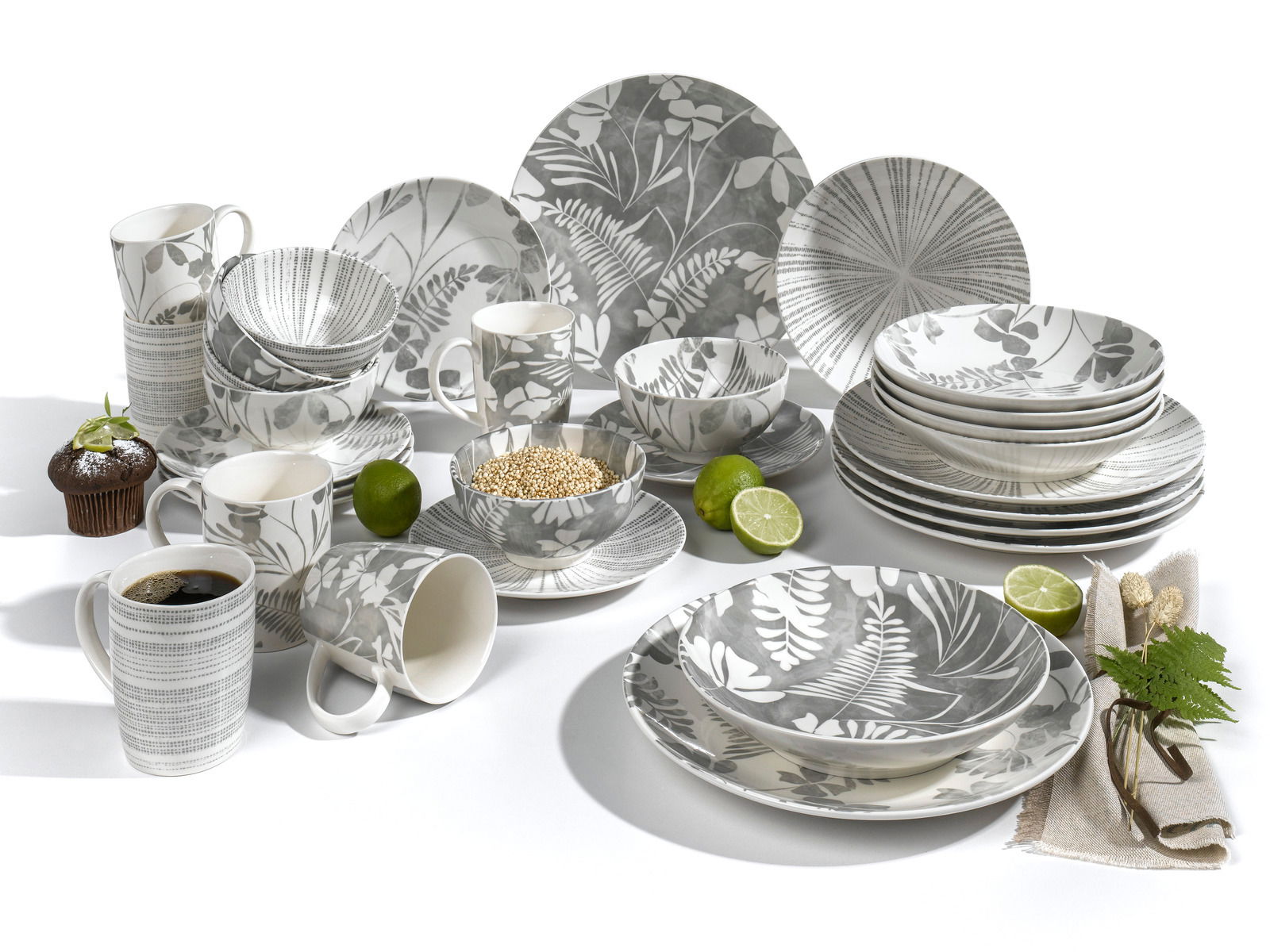 Kombiservice 30-tlg. mit grauem Blattmuster, bestehend aus Tellern, Schalen und Tassen, aus der Vogelperspektive fotografiert.