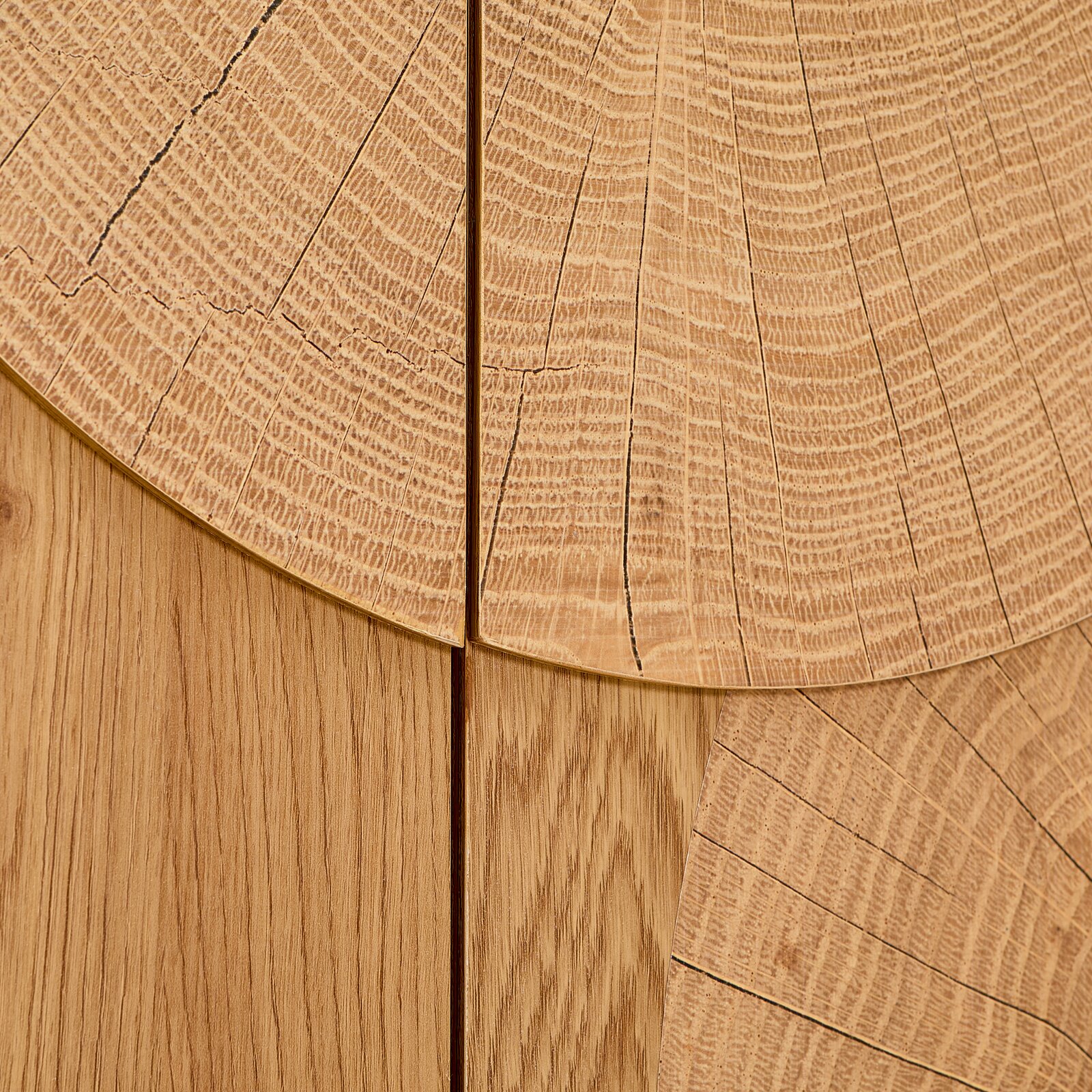 Detailaufnahme in Draufsicht: helle Holzoberfläche mit sichtbaren Jahresringen und Maserung, segmentartig zusammengesetzte Holzplatten mit feinen Rissen und Fugen