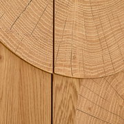 Detailaufnahme in Draufsicht: helle Holzoberfläche mit sichtbaren Jahresringen und Maserung, segmentartig zusammengesetzte Holzplatten mit feinen Rissen und Fugen