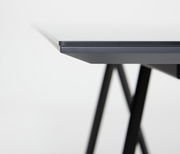 Nahaufnahme der Tischkante eines modernen Esstisches mit schwarzem Metallgestell, seitliche Perspektive