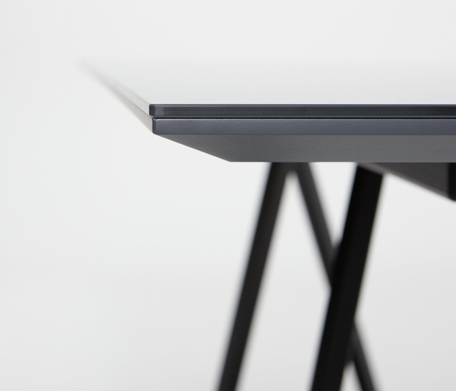 Nahaufnahme der Tischkante eines modernen Esstisches mit schwarzem Metallgestell, seitliche Perspektive