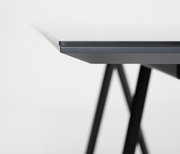 Nahaufnahme der Tischkante eines modernen Esstisches mit schwarzem Metallgestell, seitliche Perspektive