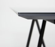 Nahaufnahme der Tischkante eines modernen Esstisches mit schwarzem Metallgestell, seitliche Perspektive